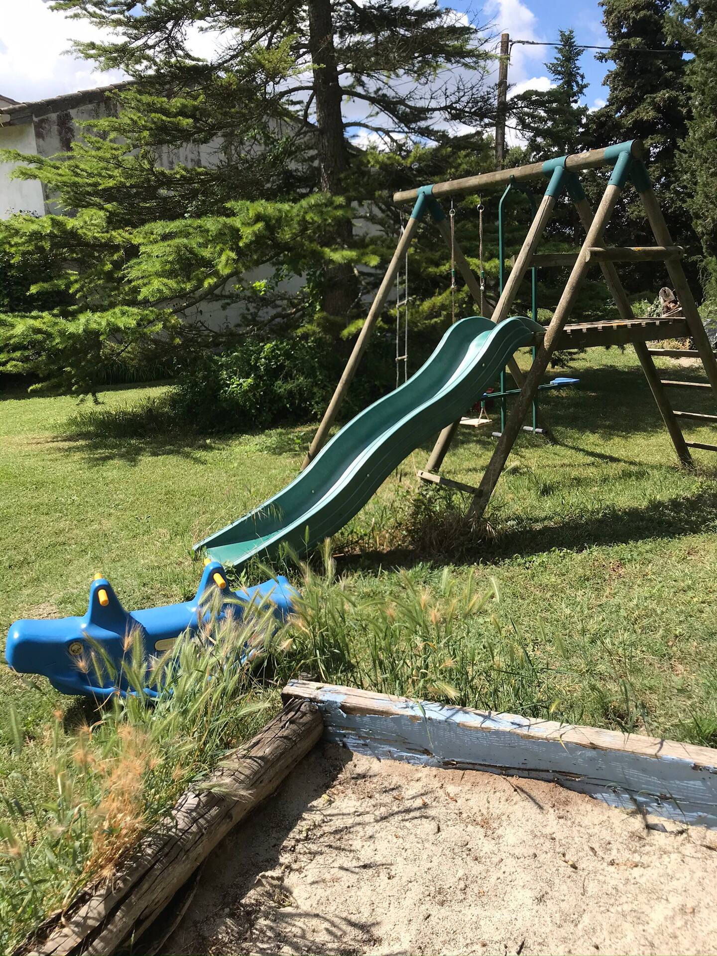 A sandpit in the foreground, with a slide and swings in the background